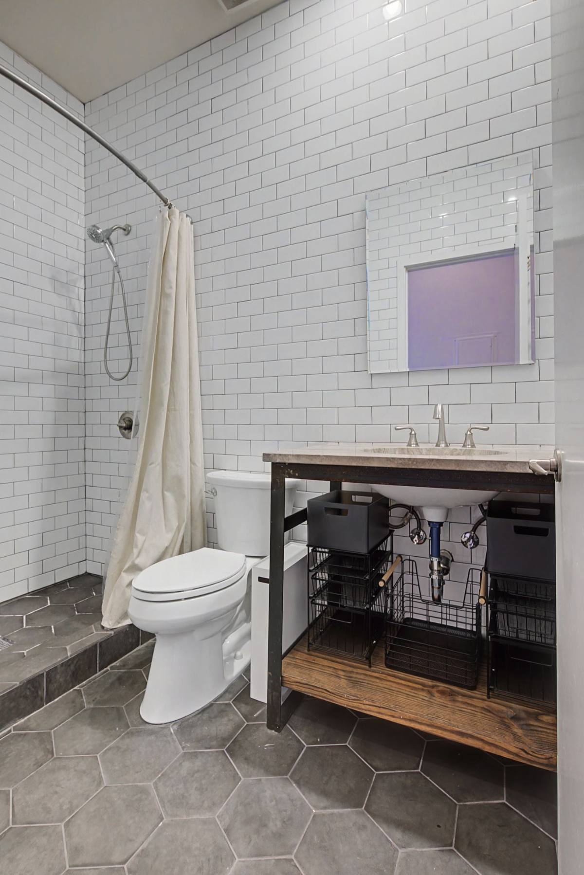 Bathroom at Residence 414 with floor-to-ceiling white subway tile, walk-in shower and an industrial-style vanity