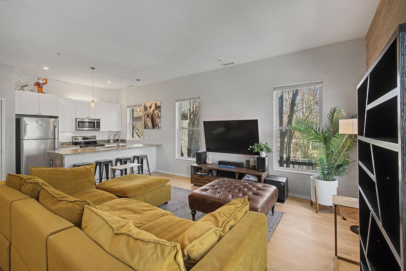 Open living area at Residence 414 with 10-foot ceilings, sectional sofa and the kitchen island beyond, 1200 5th Avenue North Historic Germantown Nashville