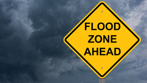 Yellow flood zone ahead warning sign under stormy skies—common concern in St. Augustine FL coastal communities.