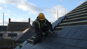 Roofer installing durable slate shingles on a St. Augustine Florida home to boost weather protection and property value.