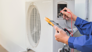 Technician testing HVAC wiring on an exterior unit during routine inspection in a St. Augustine FL home.