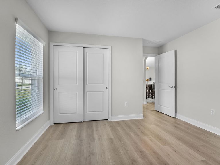 A cozy guest bedroom in a Palm Coast home featuring a comfortable bed, soft lighting, and warm, neutral decor.