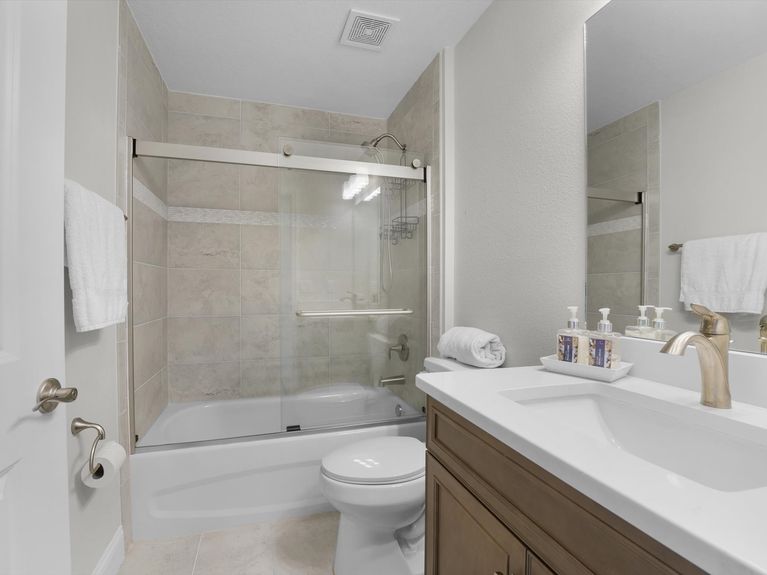 A clean and well-maintained bathroom in a Palm Coast home, featuring a bathtub with tiled surround, a vanity with storage, and modern fixtures.