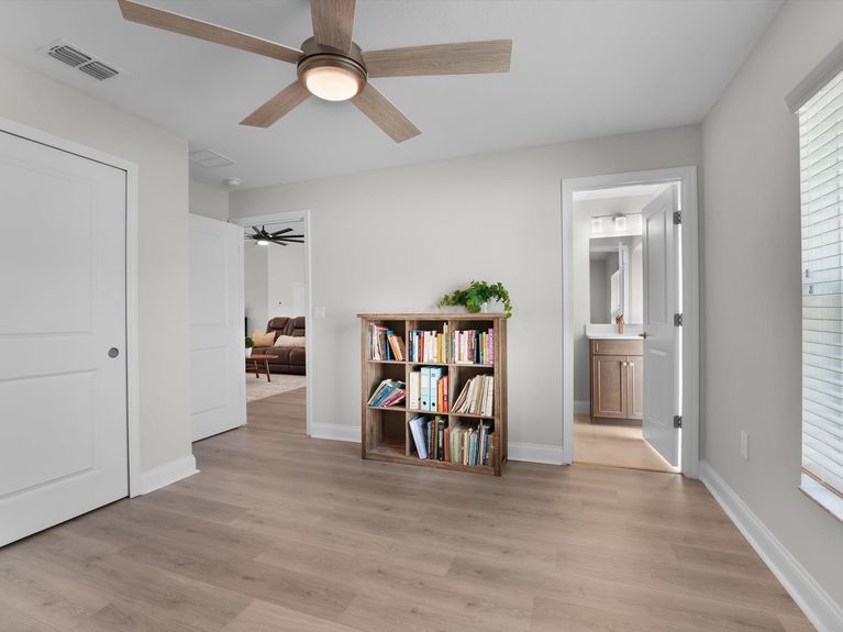A cozy guest bedroom in a Palm Coast home featuring a comfortable bed, stylish decor, and a private ensuite bathroom with modern finishes.