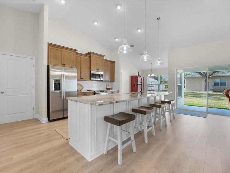 A sleek kitchen in a Palm Coast home featuring modern cabinetry, stainless steel appliances, and a spacious island with seating.