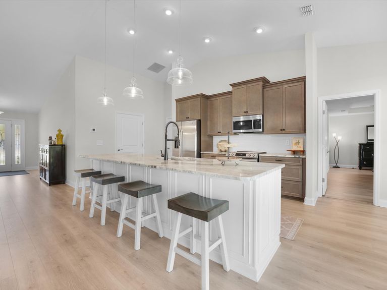 A sleek kitchen in a Palm Coast home featuring modern cabinetry, stainless steel appliances, and a spacious island with seating.