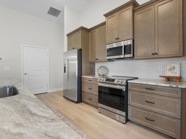 A sleek kitchen in a Palm Coast home featuring modern cabinetry, stainless steel appliances, and a spacious island with seating.