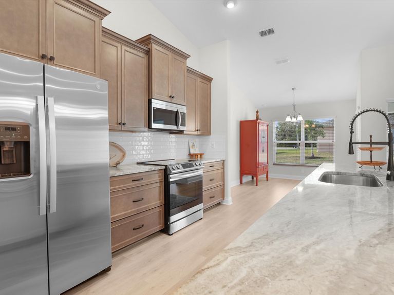 A sleek kitchen in a Palm Coast home featuring modern cabinetry, stainless steel appliances, and a spacious island with seating.