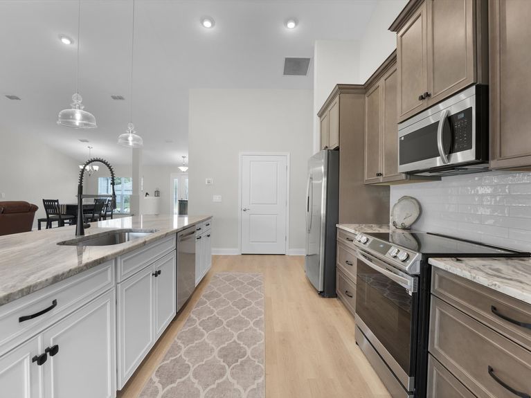 A sleek kitchen in a Palm Coast home featuring modern cabinetry, stainless steel appliances, and a spacious island with seating.