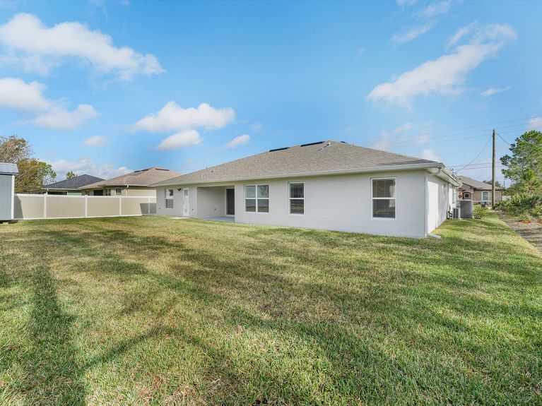 A private backyard with a covered lanai, a mature trees, and a storage shed, in Palm Coast, Florida.
