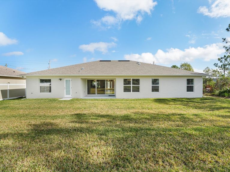 A private backyard with a covered lanai, a mature trees, and a storage shed, in Palm Coast, Florida.