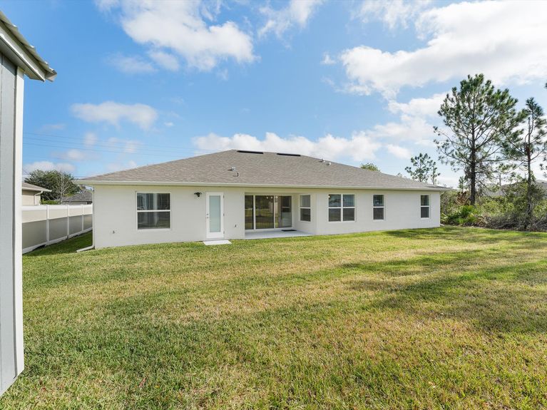 A private backyard with a covered lanai, a mature trees, and a storage shed, in Palm Coast, Florida.