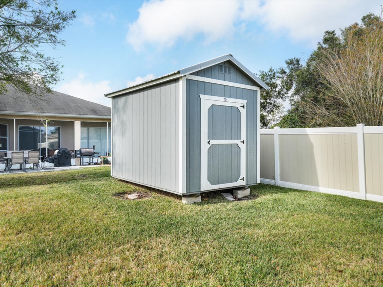 A well-maintained wooden storage shed with a gabled roof and a neatly landscaped surrounding in the backyard of a Palm Coast property.