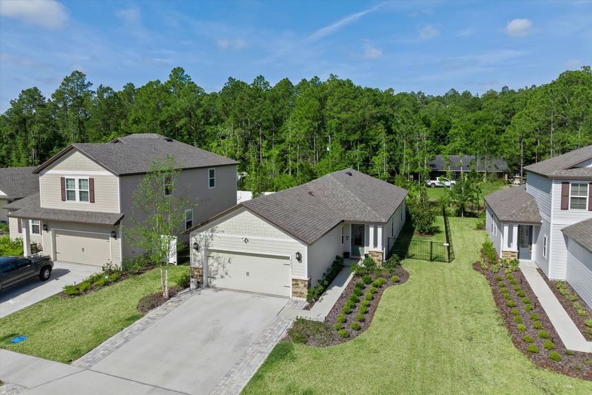 High-angle aerial view of a home, displaying the surrounding greenery and neighborhood.