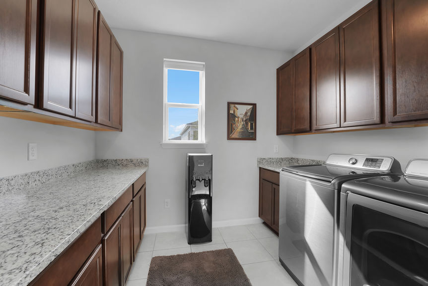 Well-designed laundry room at 50 Skyline Lane, featuring built-in cabinetry, counter space, and modern appliances in Reverie at Trailmark, St. Augustine.