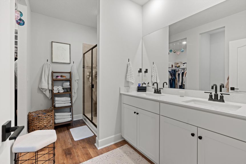 Spacious primary bathroom featuring a dual vanity, large mirror, and elegant lighting in a Morgan Cove home.