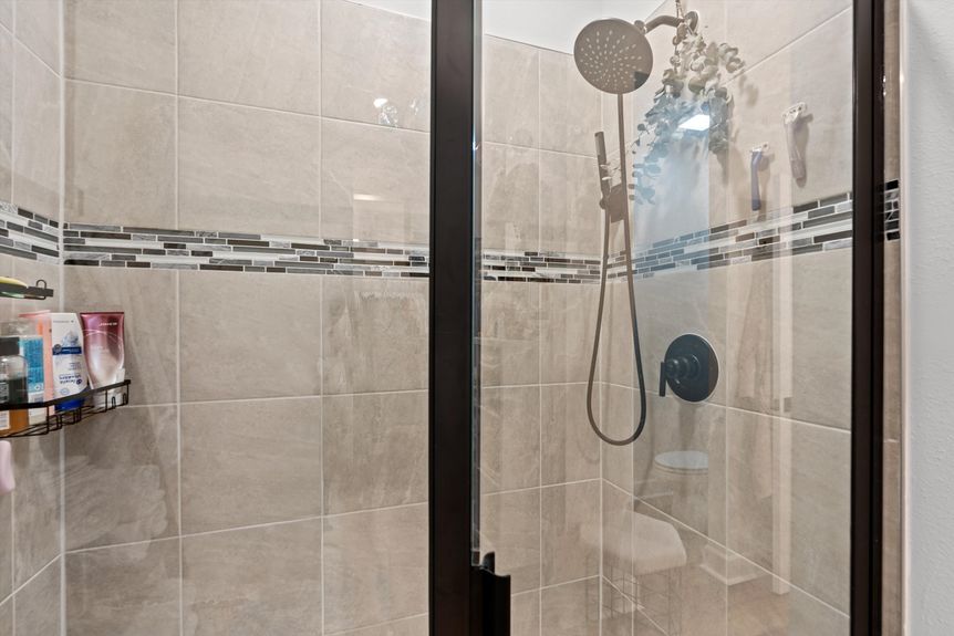 Elegant walk-in shower with a glass enclosure, sleek tilework, and a rainfall showerhead.