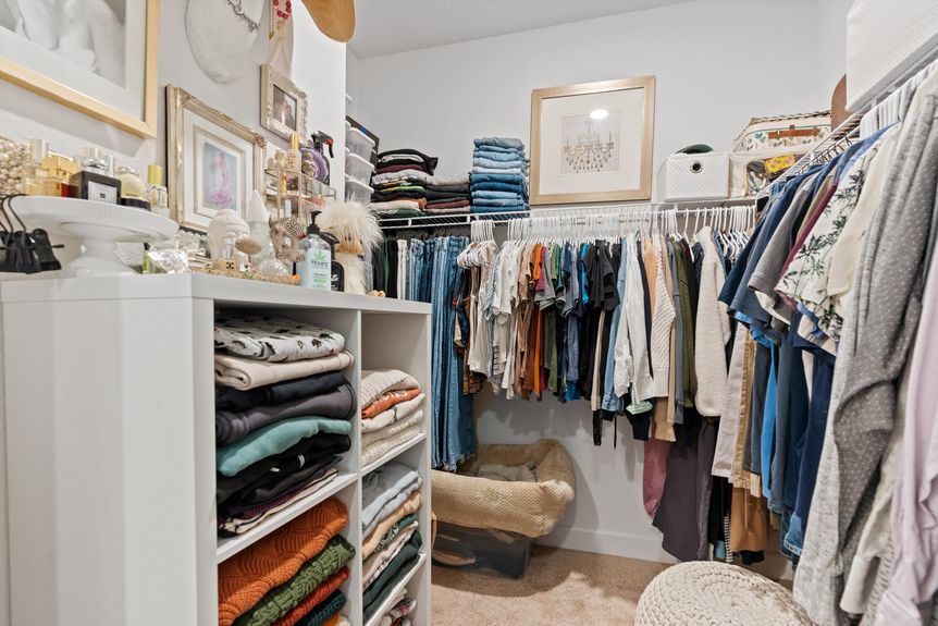 Well-organized walk-in closet with built-in shelving, ample hanging space, and soft lighting.