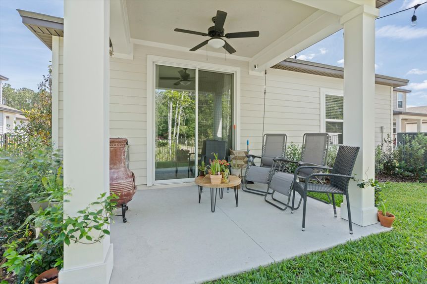 Beautiful covered patio with a ceiling fan, overlooking the backyard in a Morgan Cove home.