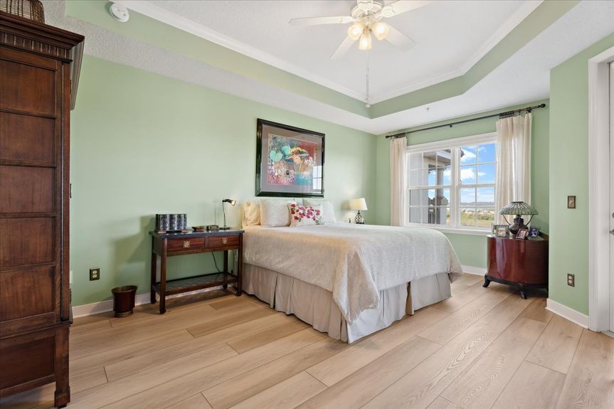 Master bedroom in a St. Augustine condo, showcasing expansive windows with picturesque marsh views.