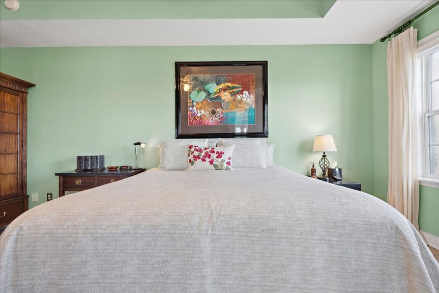 Master bedroom in a St. Augustine condo, showcasing expansive windows with picturesque marsh views.