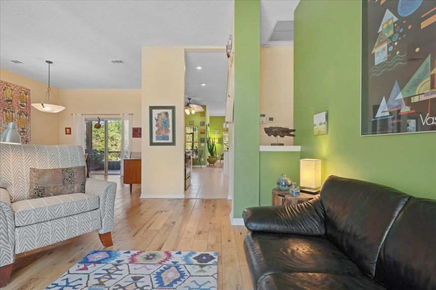 Spacious open-plan living room with hickory hardwood floors, large windows, and an inviting layout overlooking the peaceful backyard.