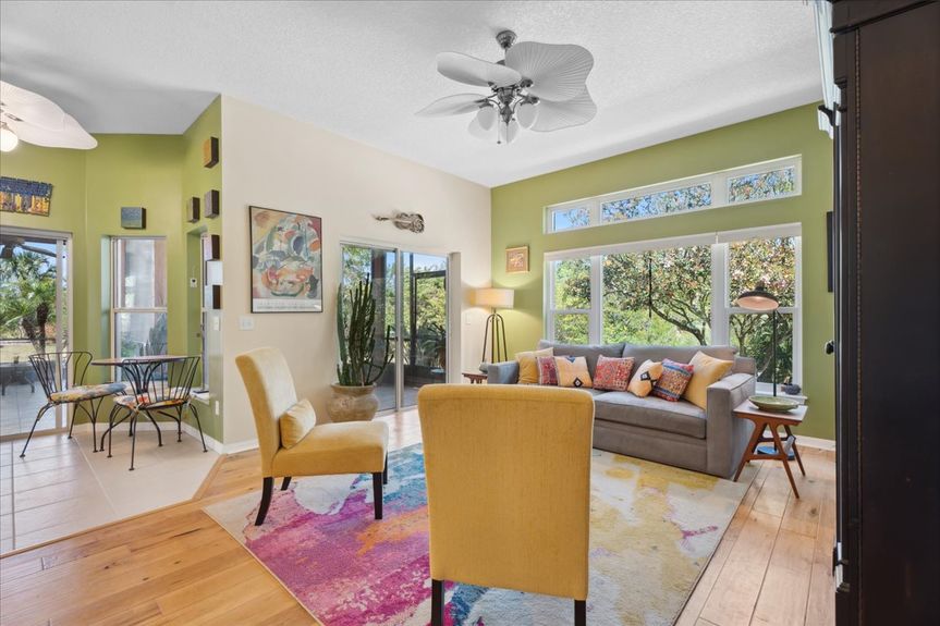 Spacious open-plan living room with hickory hardwood floors, large windows, and an inviting layout overlooking the peaceful backyard.