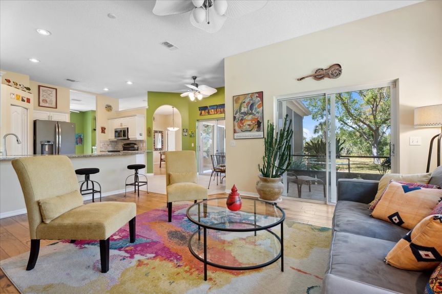 Spacious open-plan living room with hickory hardwood floors, large windows, and an inviting layout overlooking the peaceful backyard.