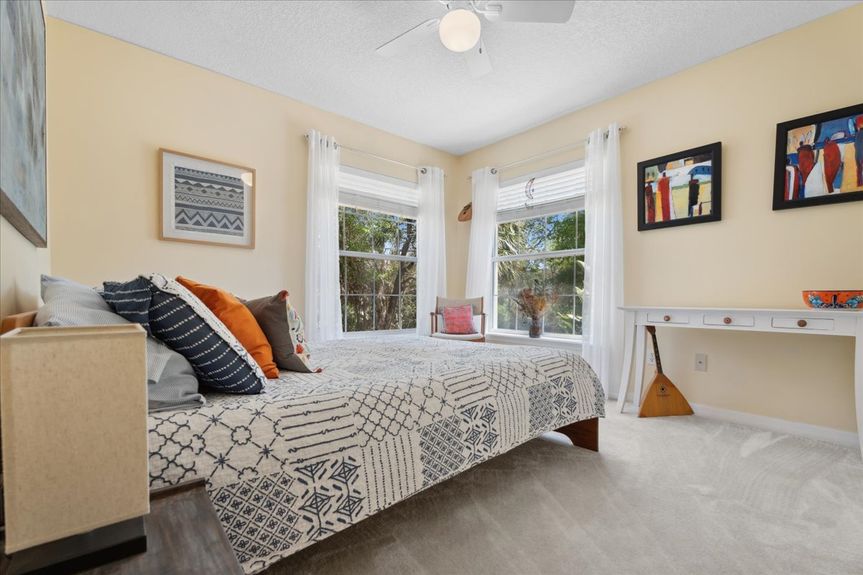 Comfortable guest bedroom at 192 Anastasia Lakes Drive, featuring soft natural light, plush carpeting, and a tranquil atmosphere.