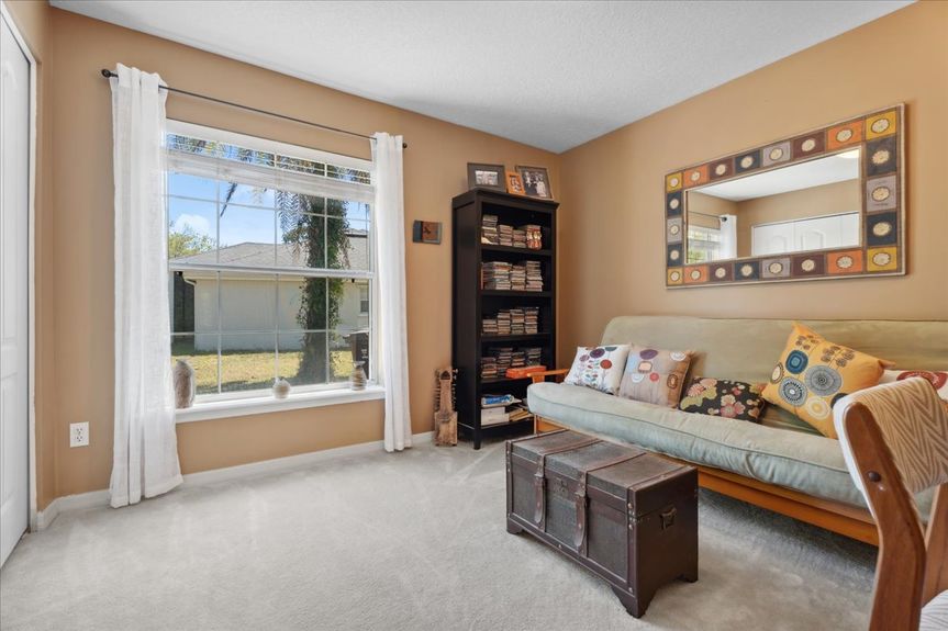 Comfortable guest bedroom at 192 Anastasia Lakes Drive, featuring soft natural light, plush carpeting, and a tranquil atmosphere.