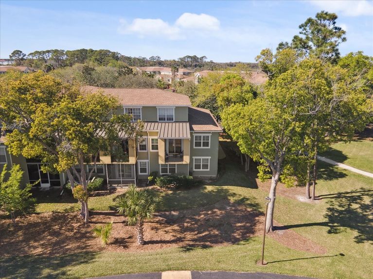Rear view of 4000 Grande Vista Blvd Unit 15-104, showcasing a private covered balcony overlooking the lush surroundings.