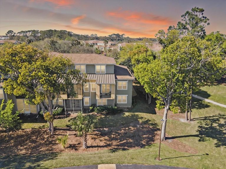 Rear view of 4000 Grande Vista Blvd Unit 15-104, showcasing a private covered balcony overlooking the lush surroundings.