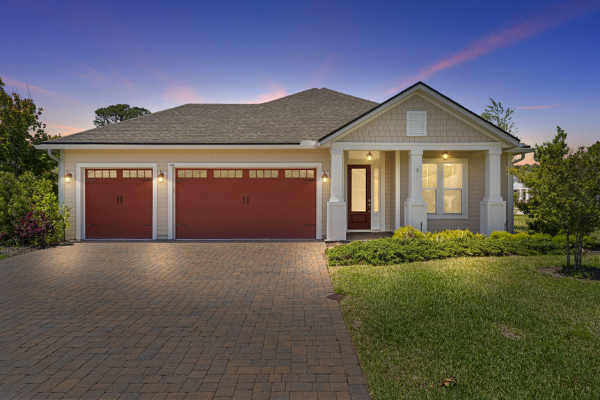 Evening Front view of a single-story Madeira home with 3-car garage and lush landscaping