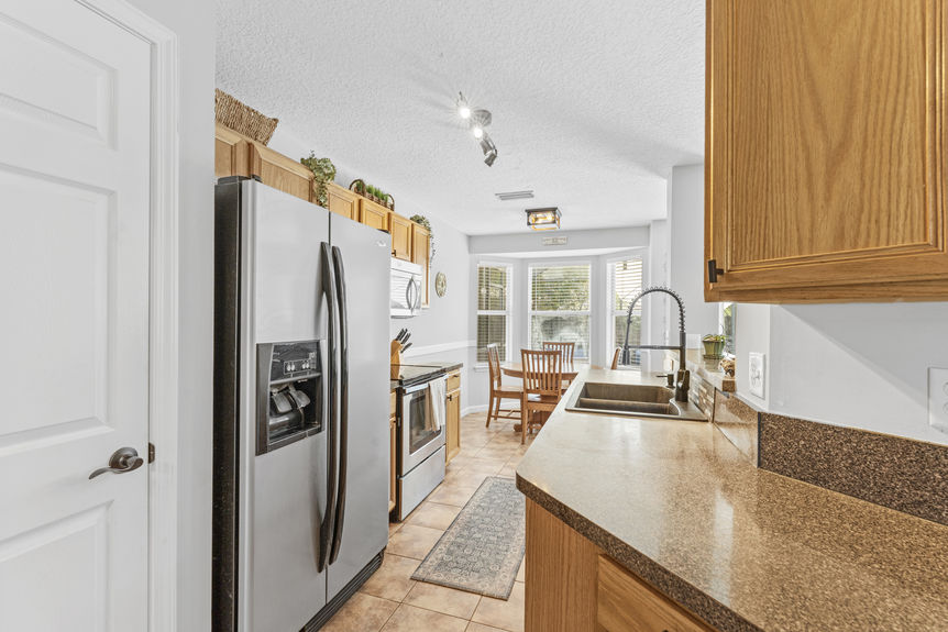 Bright kitchen with bar seating, wood cabinets, and open layout in no-HOA St. Augustine home