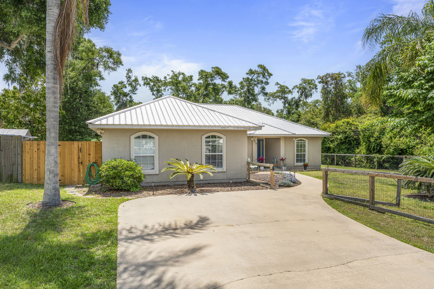 Front view of a single-story home with metal roof and fenced yard in St Augustine, Florida