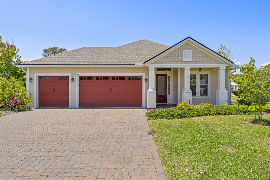 Front view of a single-story Madeira home with 3-car garage and lush landscaping