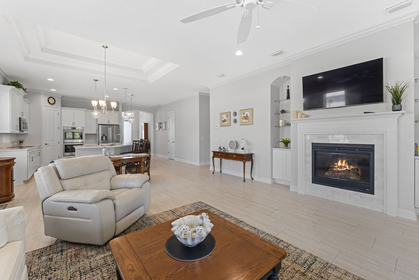 Open concept living room with large windows, tile floors, and neutral tones