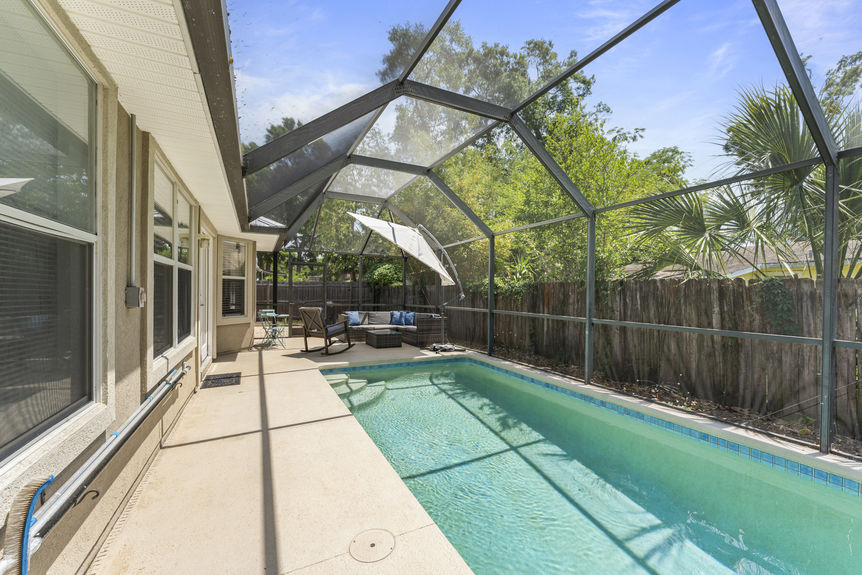 Backyard view of in-ground pool surrounded by privacy fencing and greenery in St. Augustine Florida