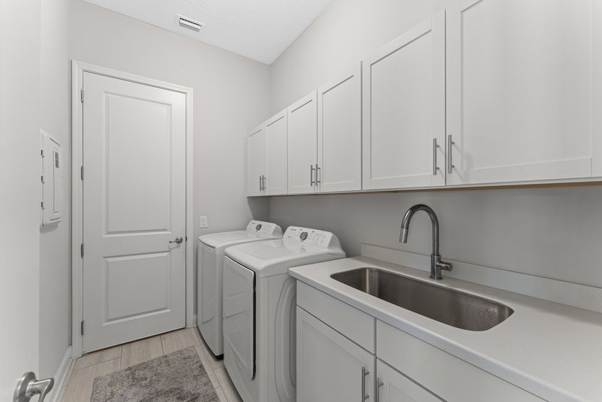 Laundry room with utility sink, upper cabinets, and washer/dryer hookups in Madeira home