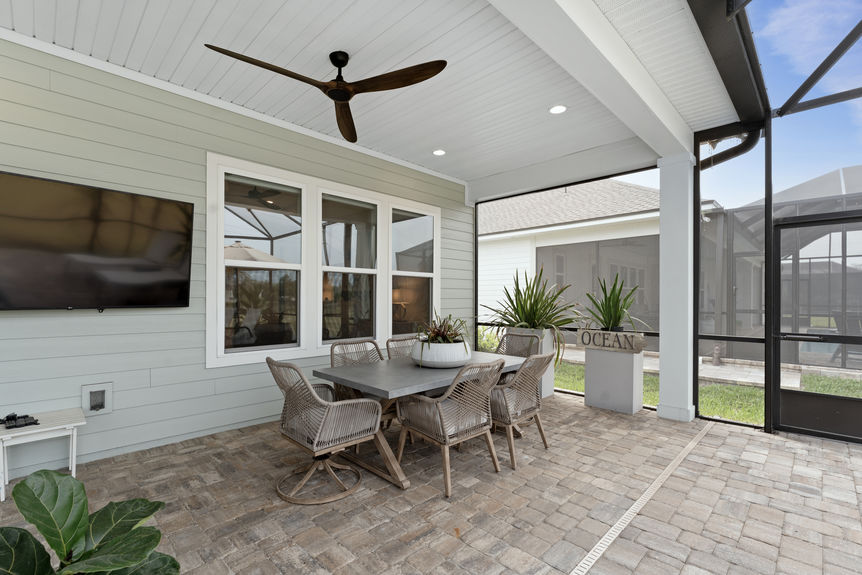Backyard featuring a screened-in pool with surrounding patio and lush landscaping