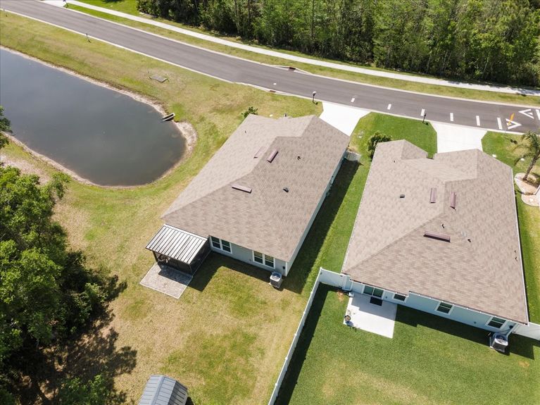 Aerial front view of a single-story move-in ready home with 3 bedrooms, 2 baths, screened lanai, and pond views near community pool, pickleball courts, and fitness center.