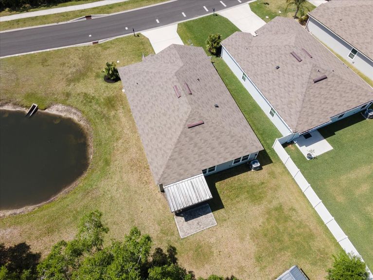 Aerial front view of a single-story move-in ready home with 3 bedrooms, 2 baths, screened lanai, and pond views near community pool, pickleball courts, and fitness center.