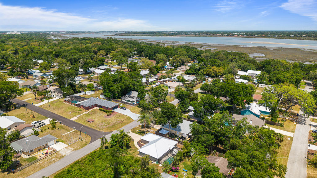 Aerial view of St. Augustine South 4-bedroom pool home with fenced yard, screened lanai, metal roof, guest suite, and space for RV or boat—no HOA.