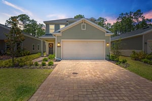 Front view of two-story home with paved driveway, landscaped yard, and two-car garage in St Augustine, Florida
