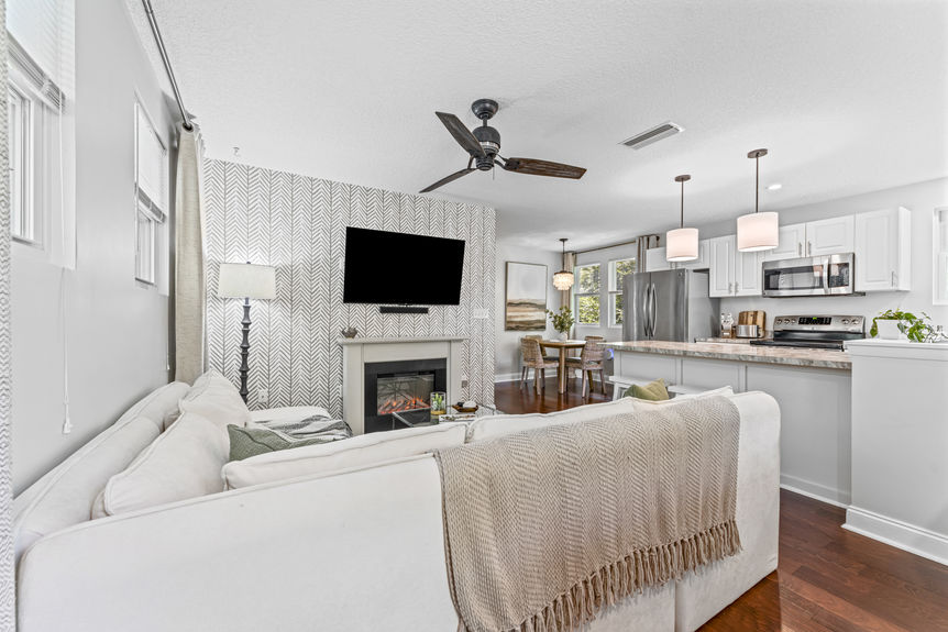 Spacious living room with wood floors, electric fireplace, and open layout in a St. Augustine home