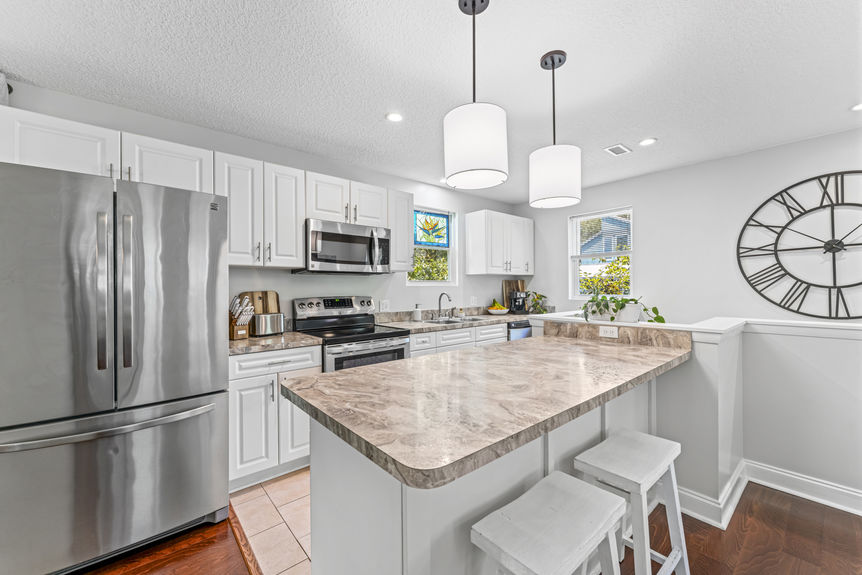 Bright modern kitchen with stainless steel appliances, white cabinetry, and marble countertops in a St. Augustine home