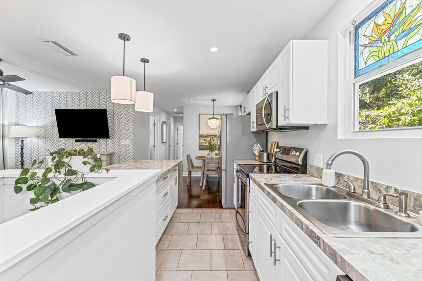 Bright modern kitchen with stainless steel appliances, white cabinetry, and marble countertops in a St. Augustine home