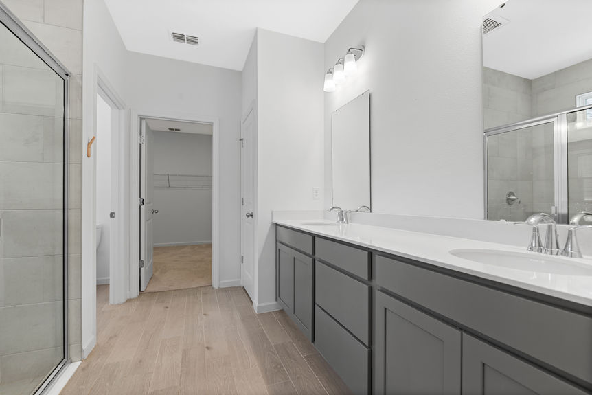 Modern bathroom with dual sinks, large mirror, and glass walk-in shower in St Augustine home