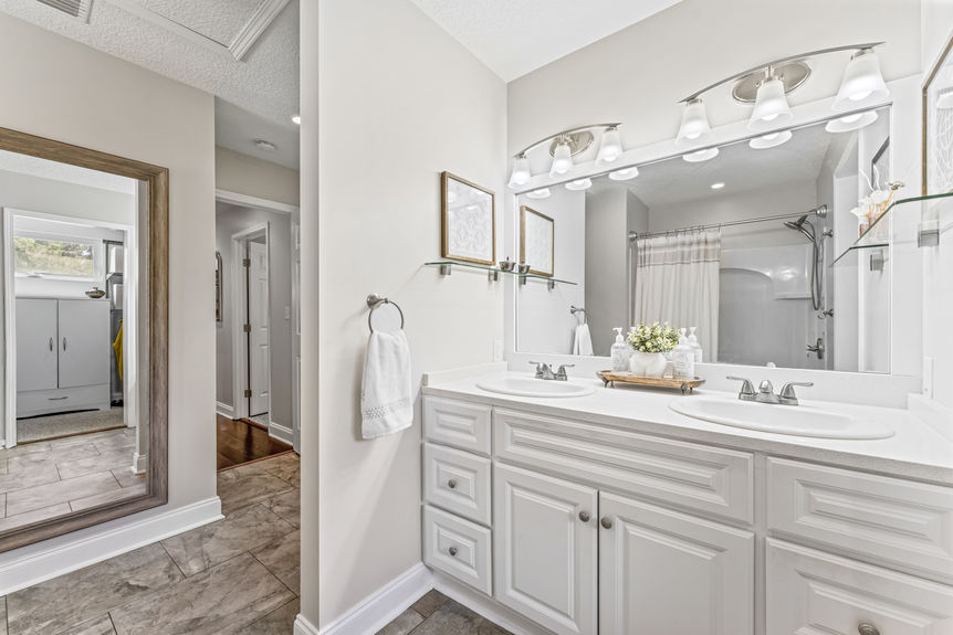 Bright bathroom with double sinks, white cabinetry, and modern lighting in a St. Augustine home