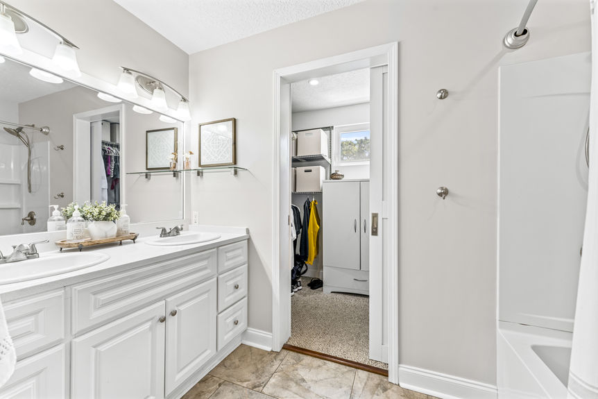 Bright bathroom with double sinks, white cabinetry, and modern lighting in a St. Augustine home